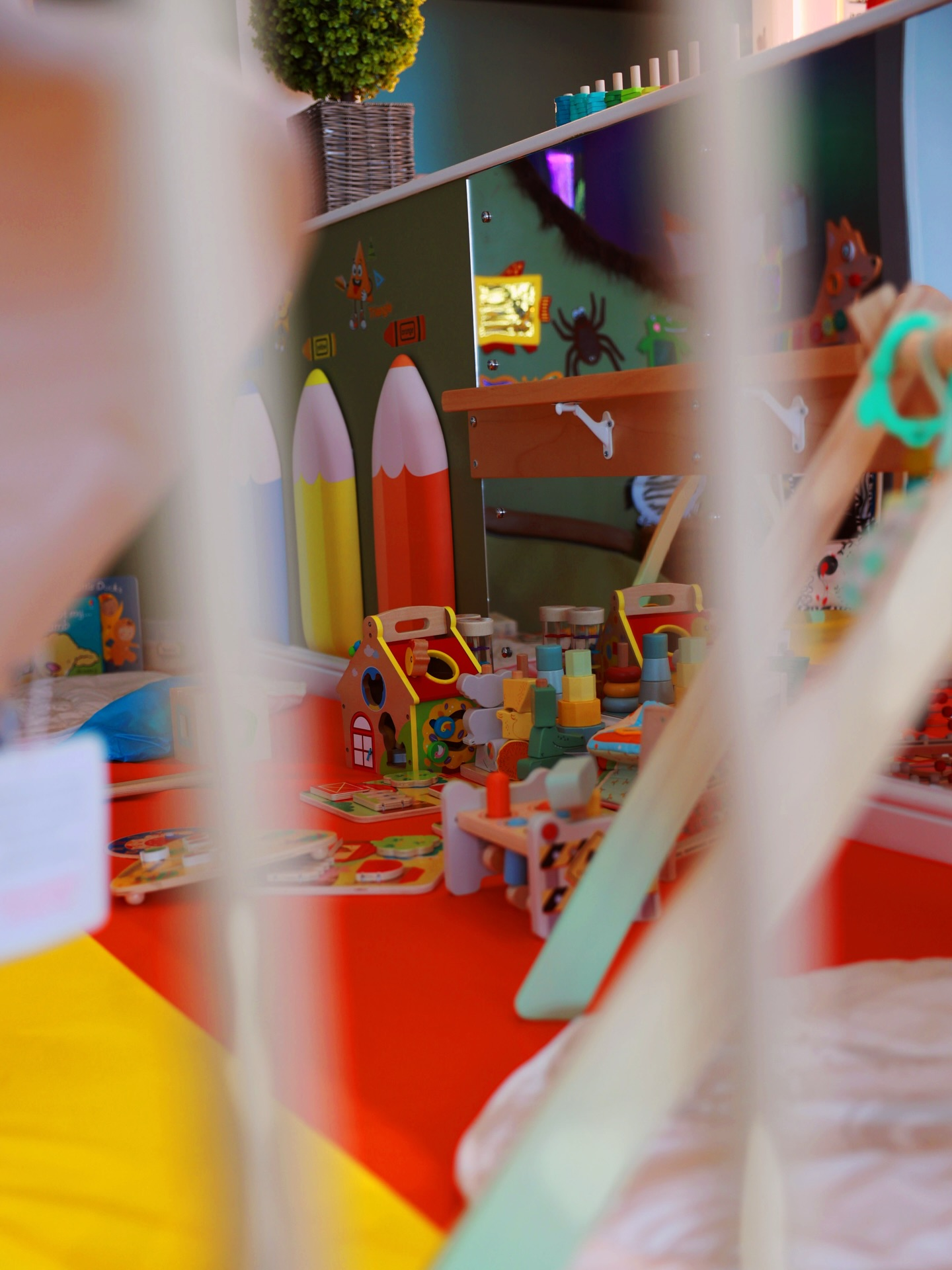 Colourful toddler safe zone with wooden toys and giant pencils